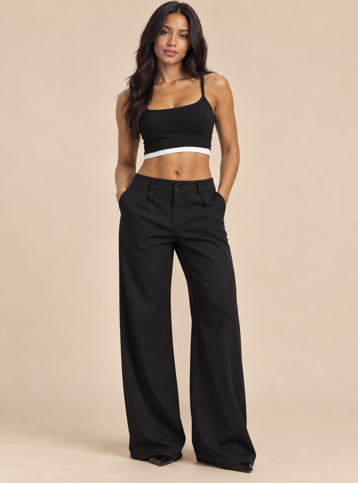 A woman modeling a black crop top with a white band and black wide-leg pants against a solid beige studio background.