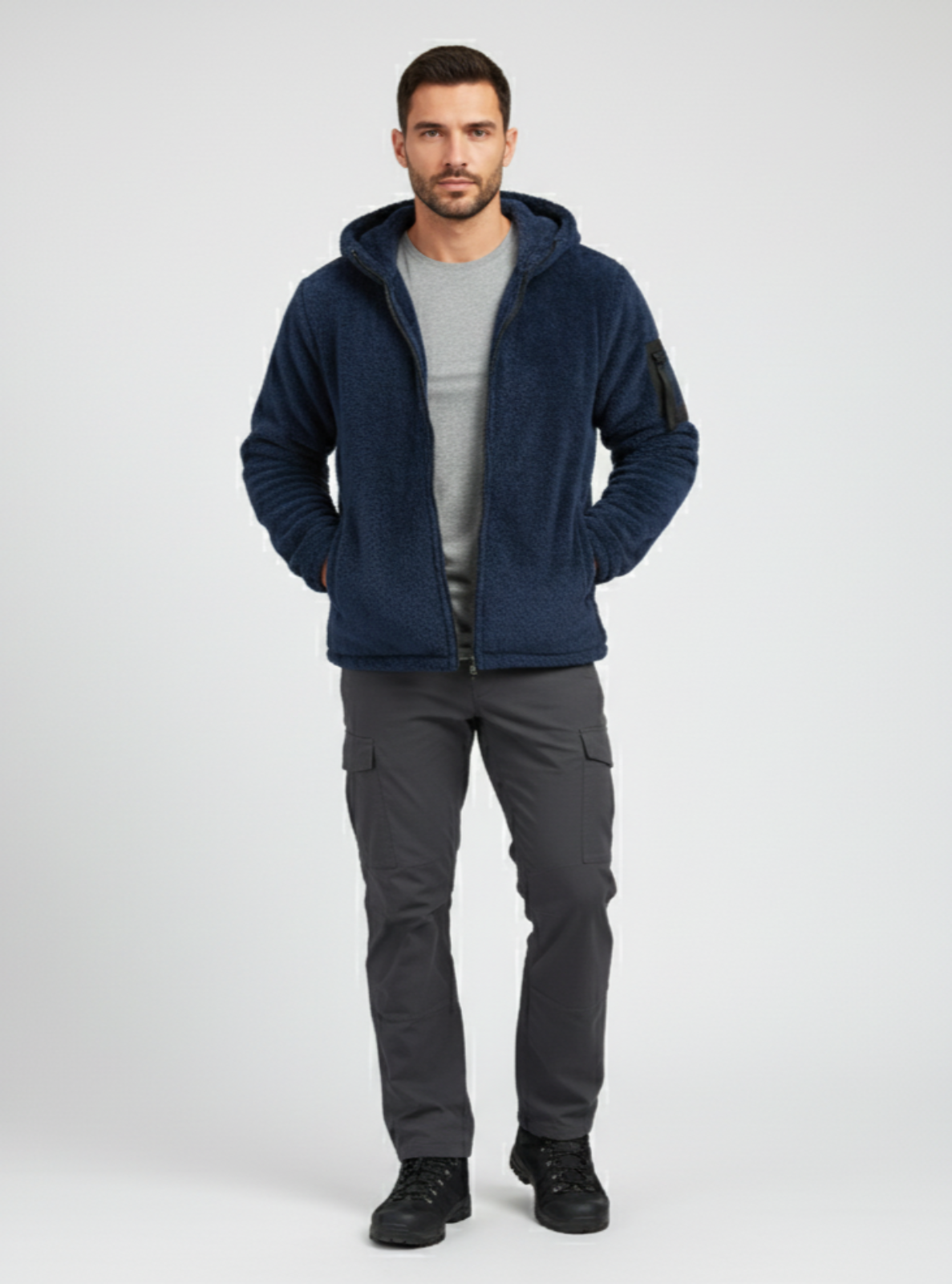 Man wearing a navy blue hooded jacket and gray pants on a white background