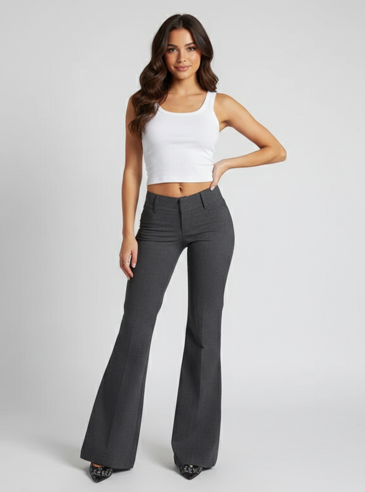 Woman wearing a white tank top and gray flared pants on a light gray background