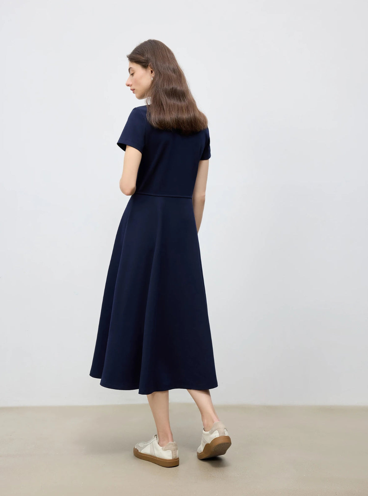 Woman wearing a navy blue dress on a plain background