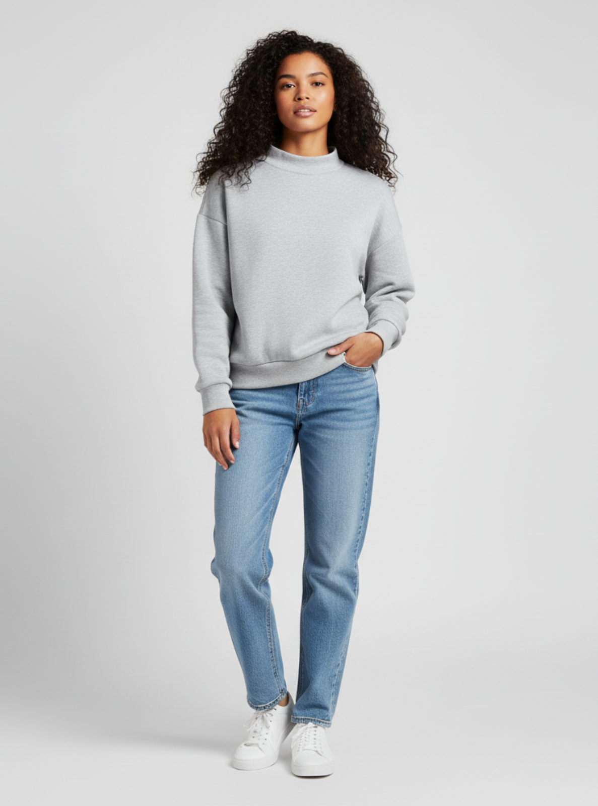 Woman wearing a light gray sweatshirt and blue jeans on a white background