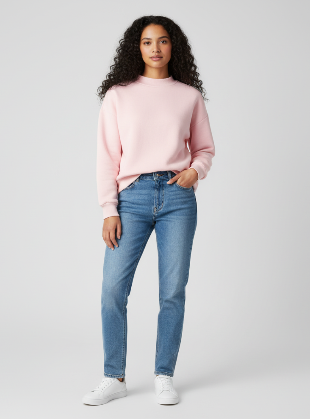 Woman wearing a pink sweater and blue jeans on a white background