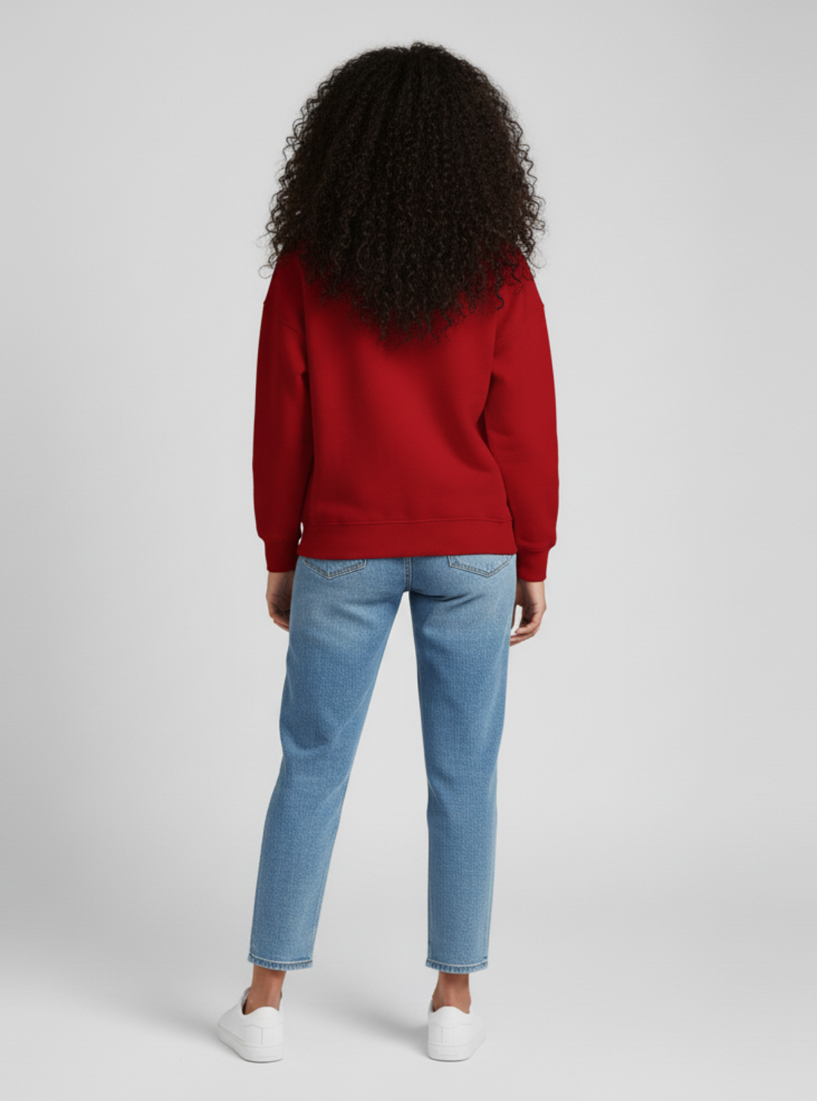 Person wearing a red sweatshirt and blue jeans on a light gray background