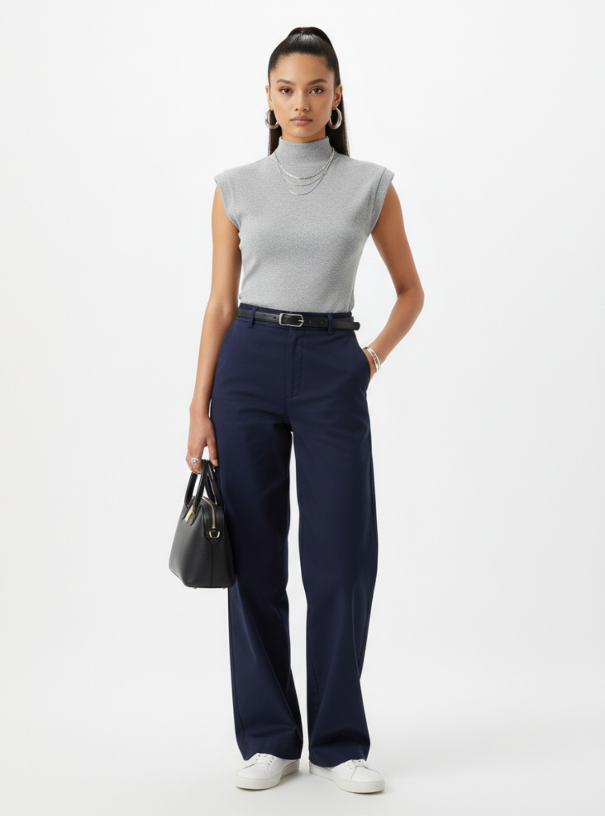 Woman wearing a gray sleeveless top and navy pants on a white background