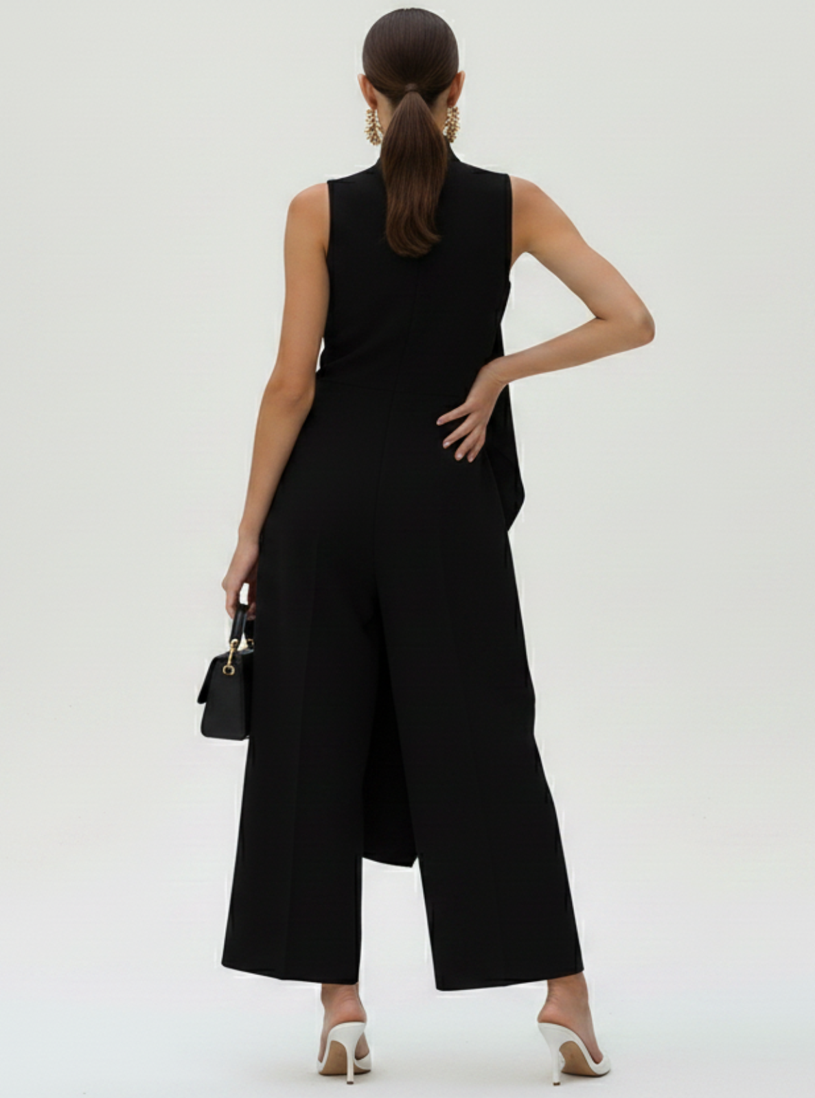 Woman wearing a black sleeveless jumpsuit on a white background
