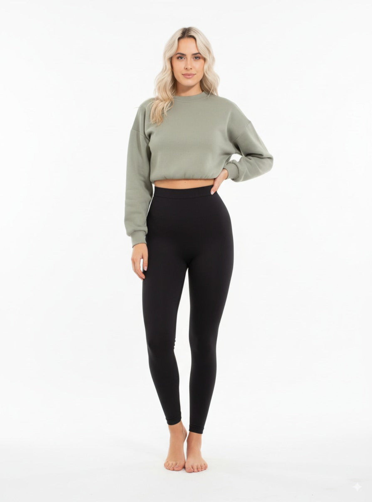 Woman wearing a green cropped sweatshirt and black leggings on a white background