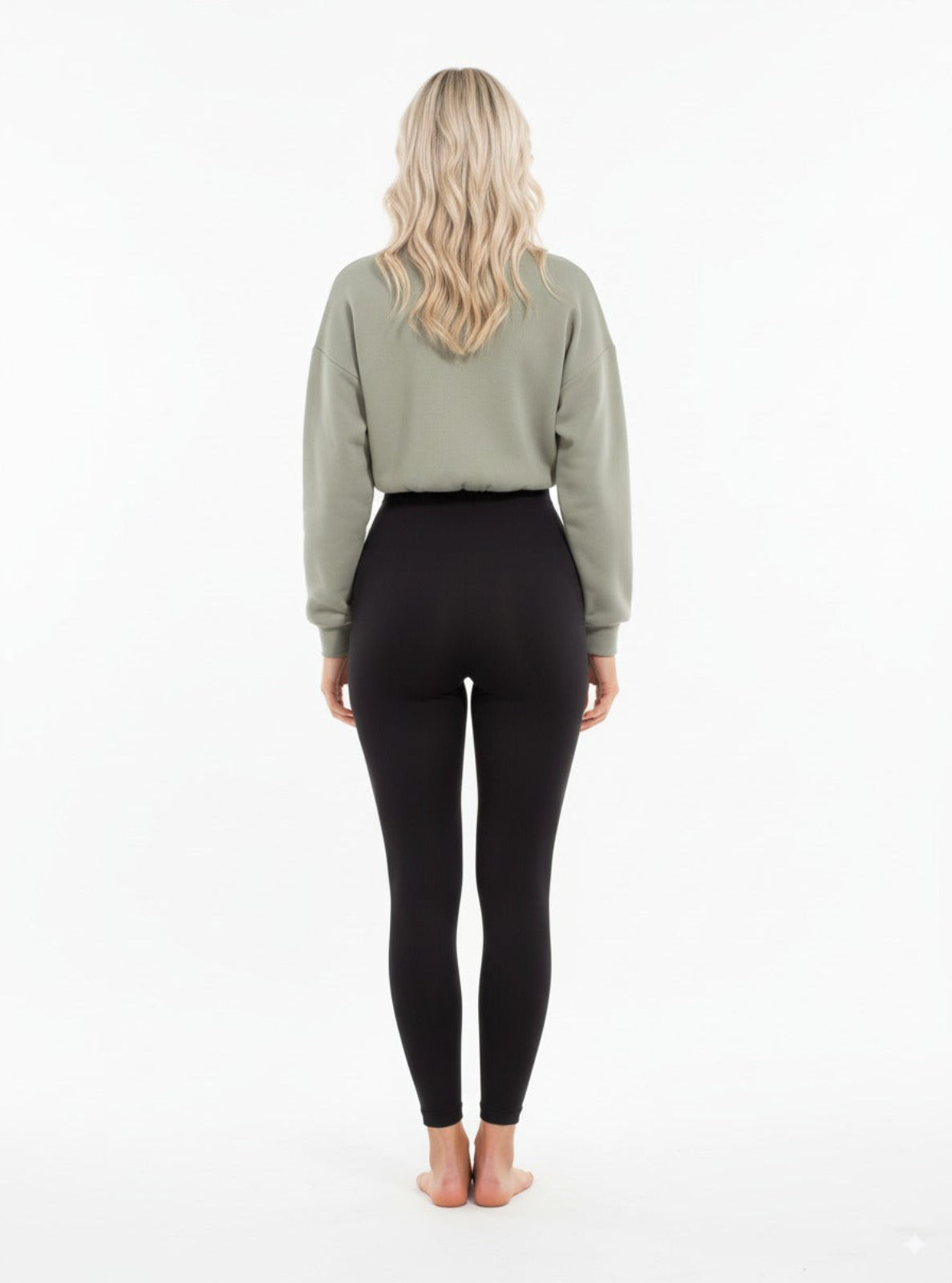 Person wearing black leggings and a green crop top on a white background