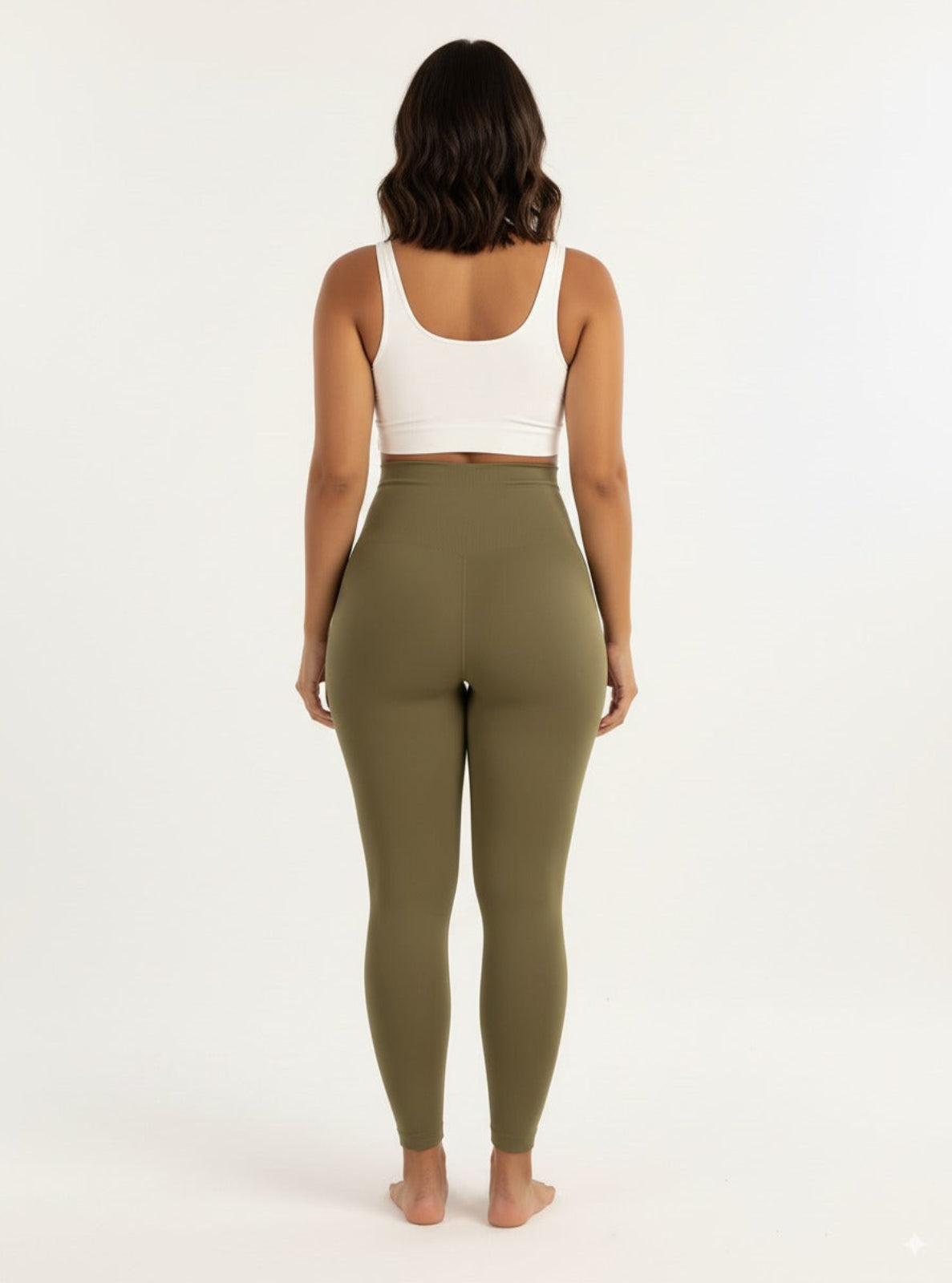 Person wearing olive green leggings and a white crop top on a white background
