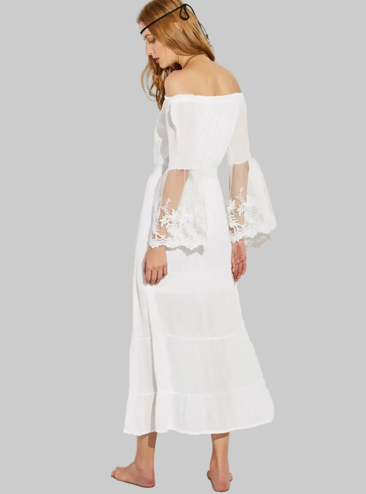 Woman wearing a white off-shoulder dress with lace sleeves on a gray background