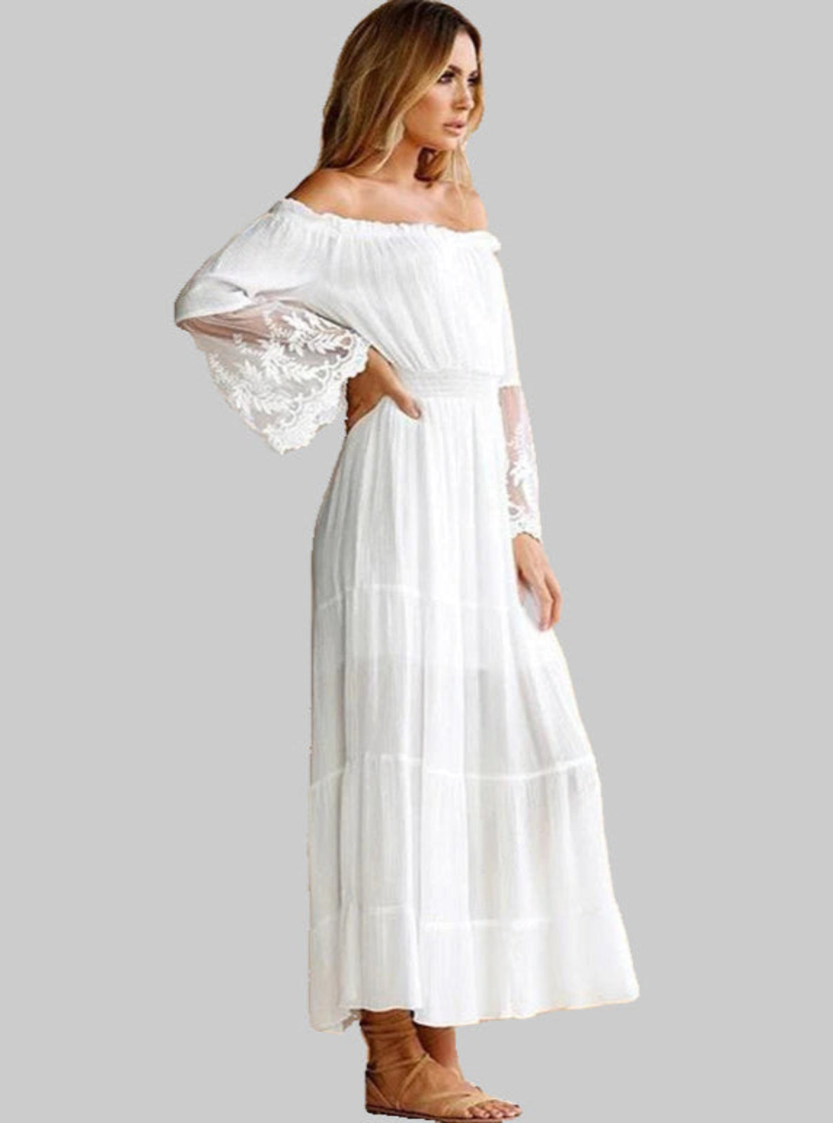 Woman wearing a white off-shoulder dress with sheer sleeves on a gray background