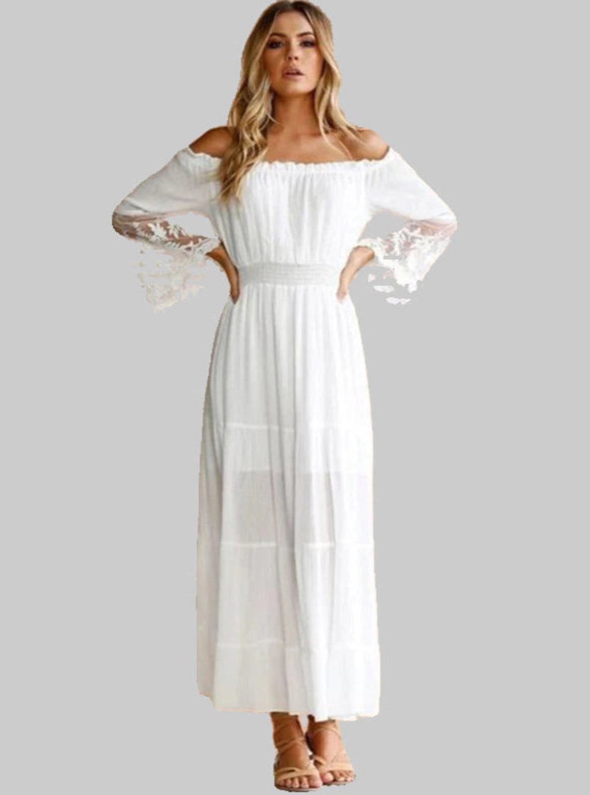 Woman wearing a white off-shoulder dress with sheer sleeves on a gray background