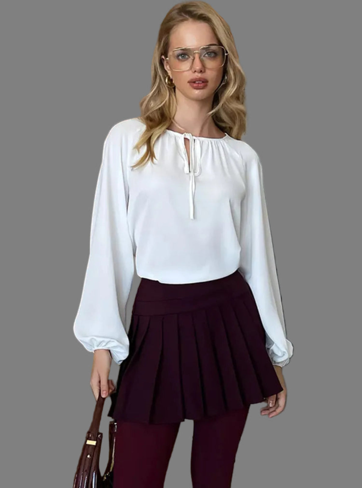 Woman wearing a white blouse and maroon skirt standing indoors.