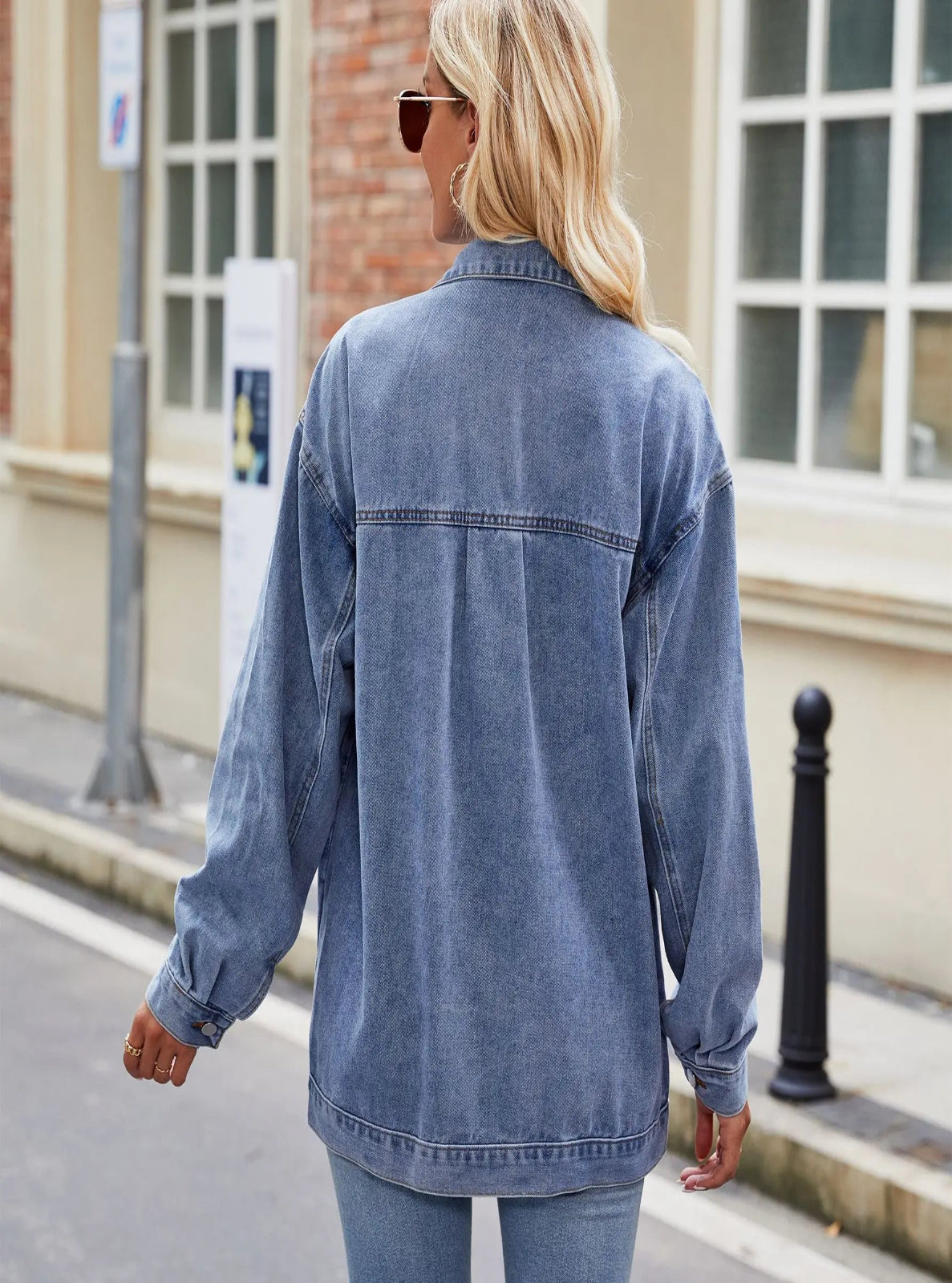 Woman wearing a denim jacket walking on a street.