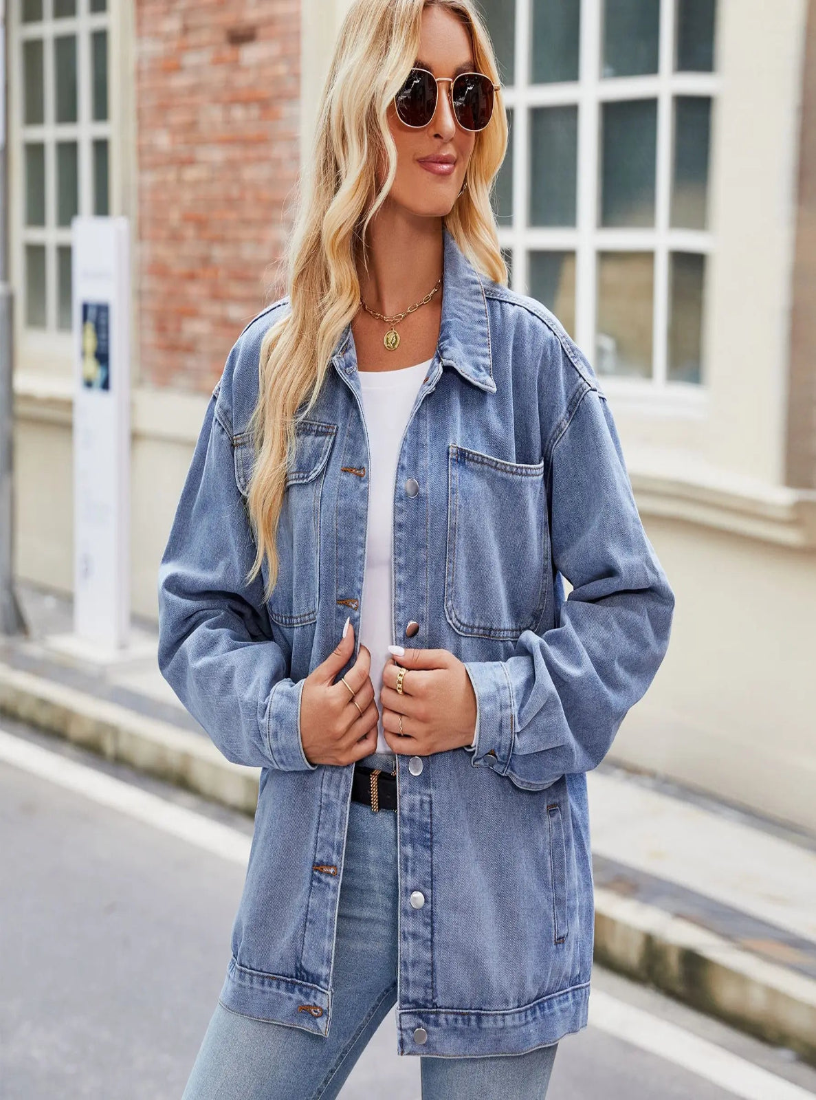 Woman wearing a denim jacket and sunglasses on a street.