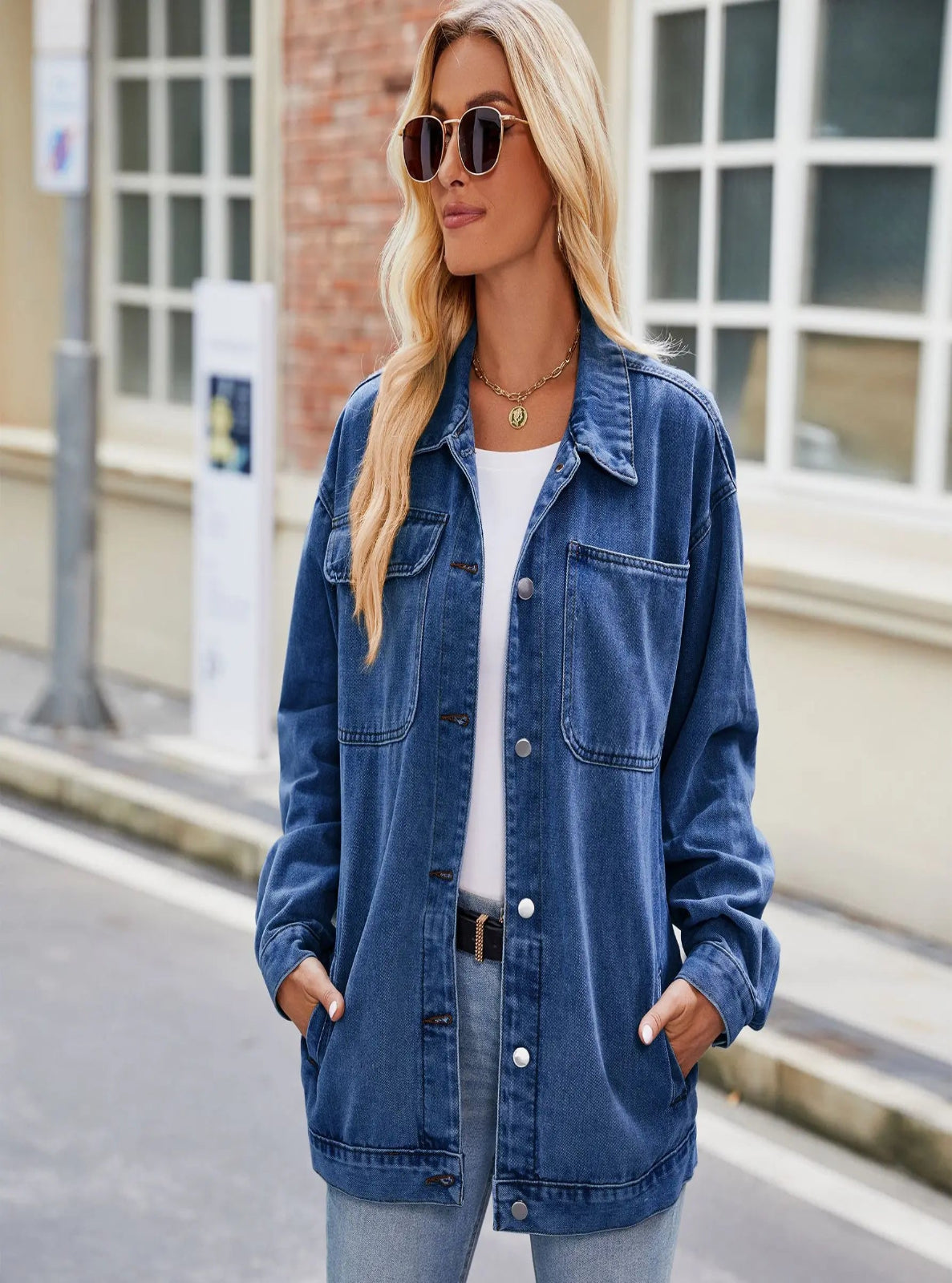 Woman wearing a blue denim jacket and sunglasses on a city street.