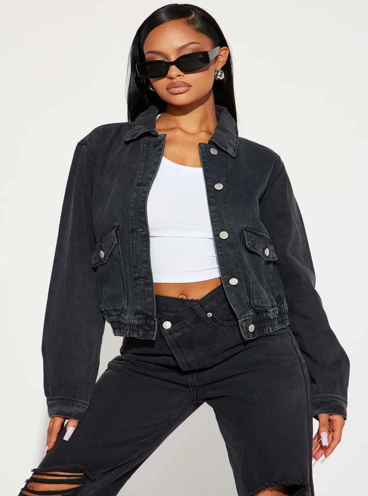Woman wearing a black denim jacket and black pants on a white background