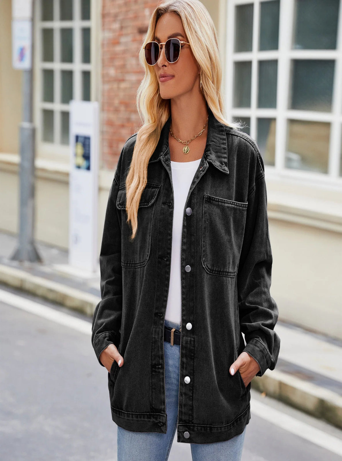 Woman wearing a black denim jacket, white shirt, and blue jeans on a city street.