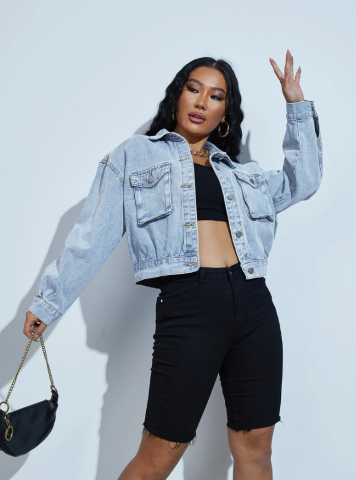 Woman wearing a denim jacket and black shorts against a light background