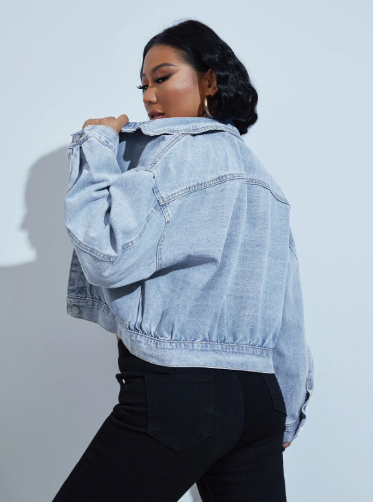 Person wearing a light blue denim jacket against a plain background