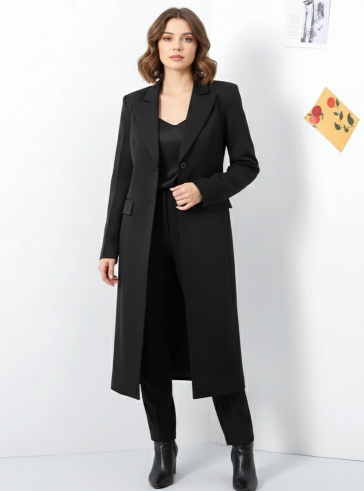 Woman wearing a long black coat against a white background