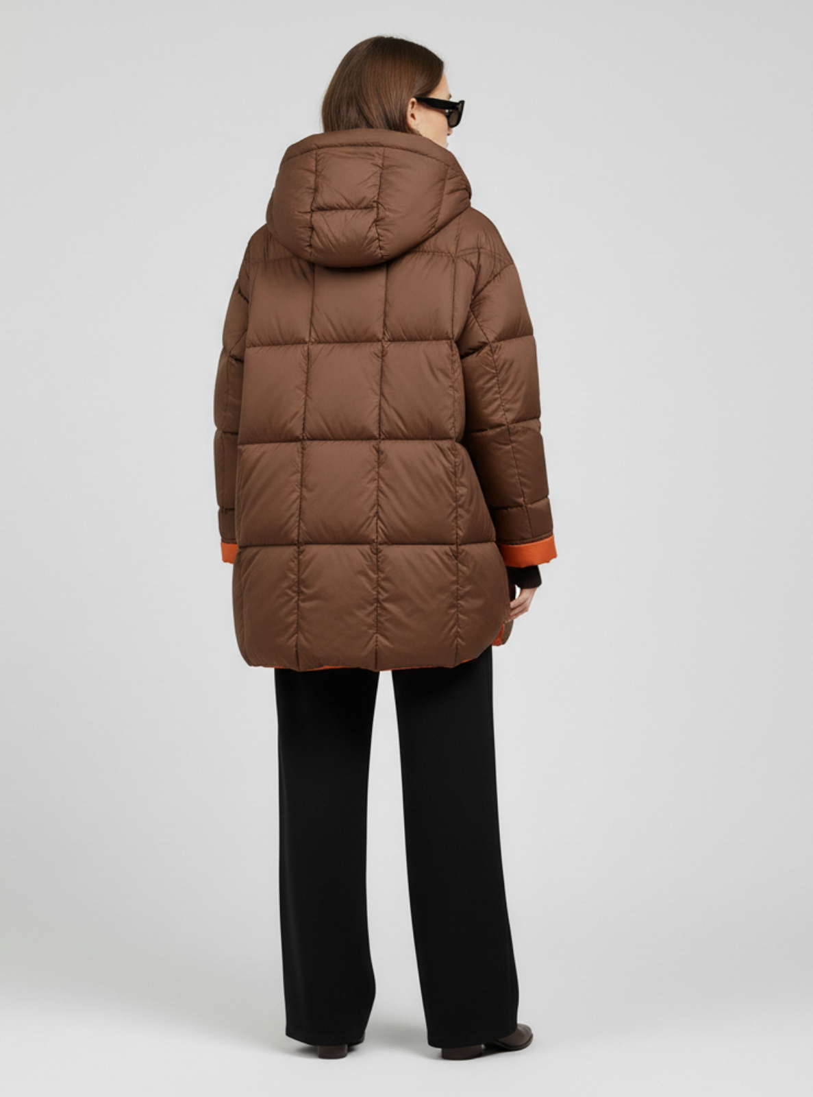 Person wearing a brown puffer coat on a light gray background