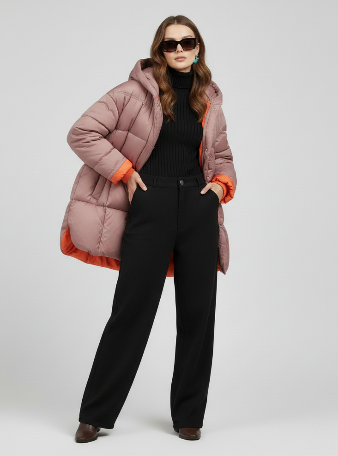Woman wearing a pink puffer jacket with orange trim on a white background