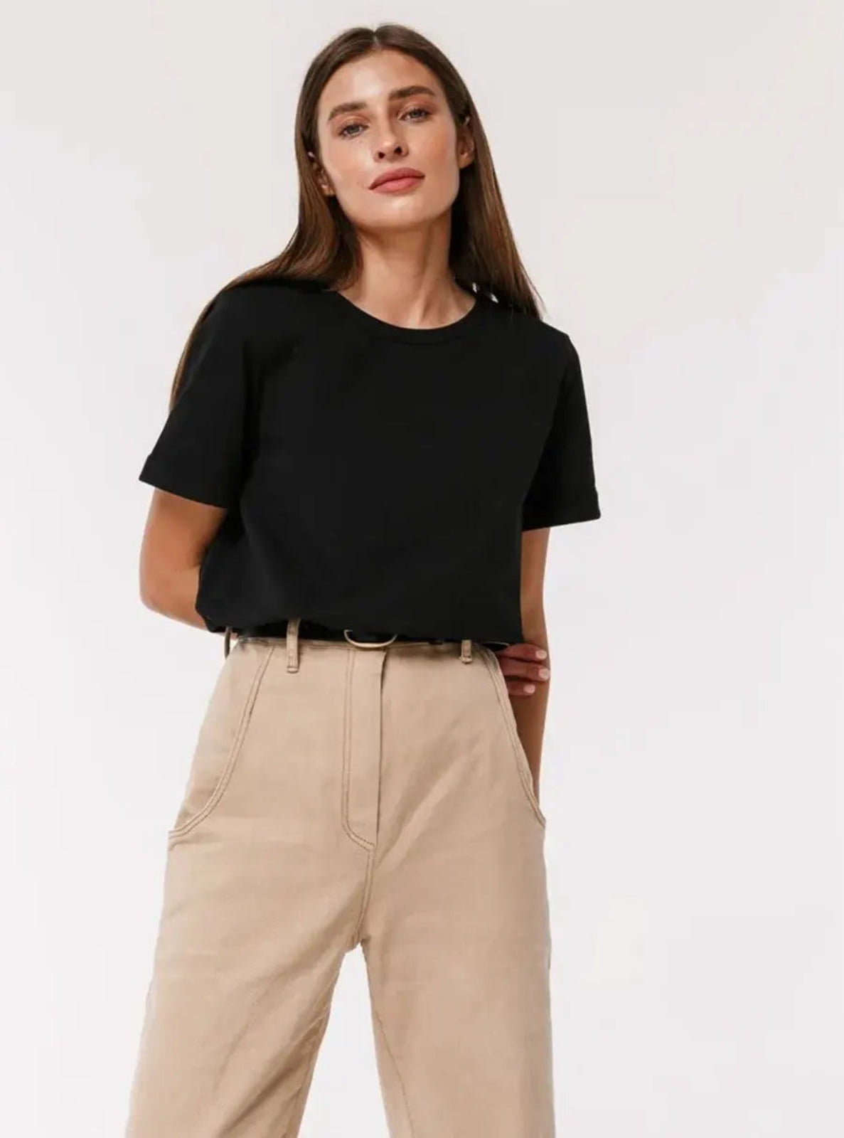 Woman wearing a black t-shirt and beige pants on a white background