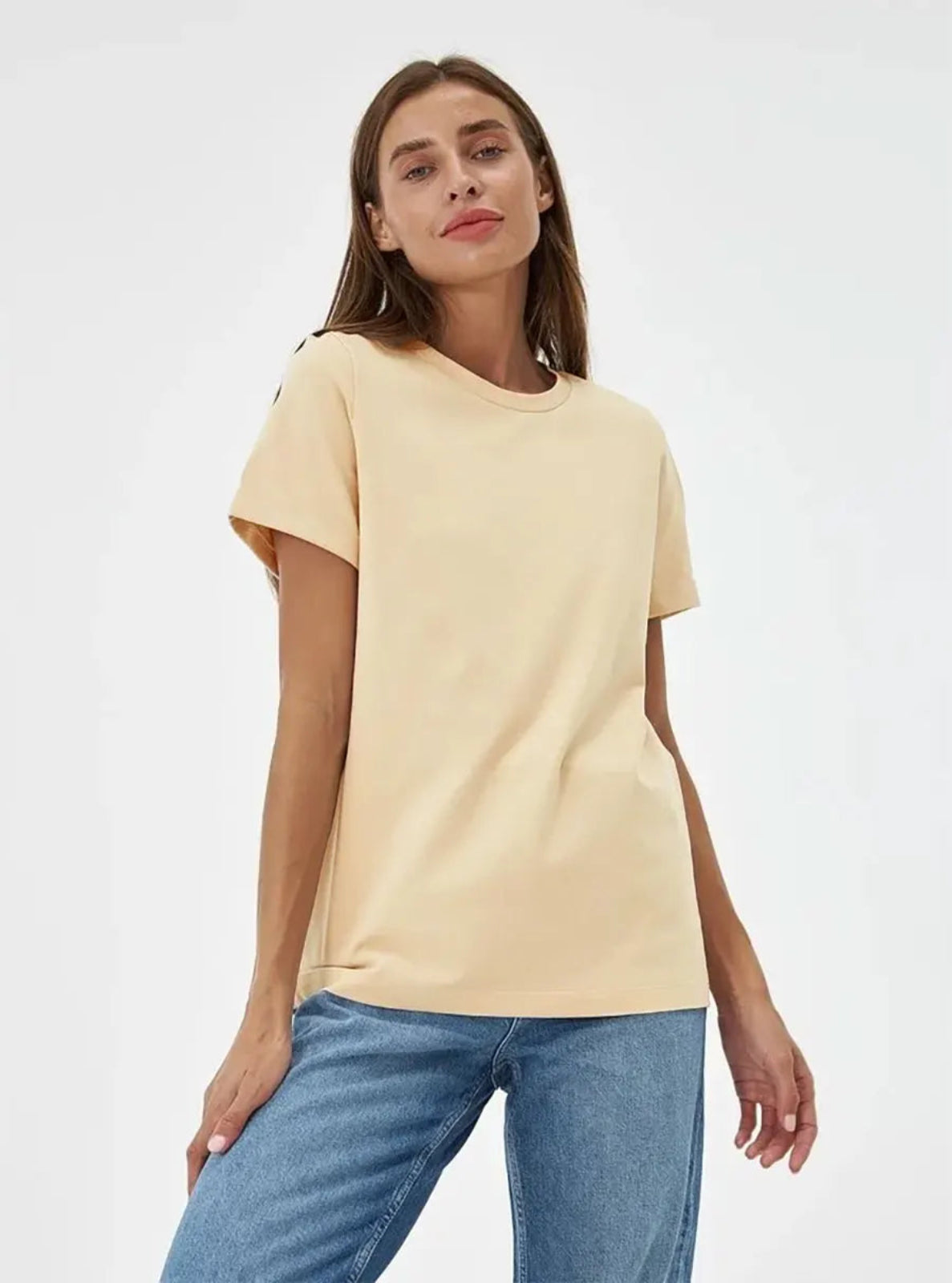 Woman wearing a beige t-shirt and blue jeans on a white background