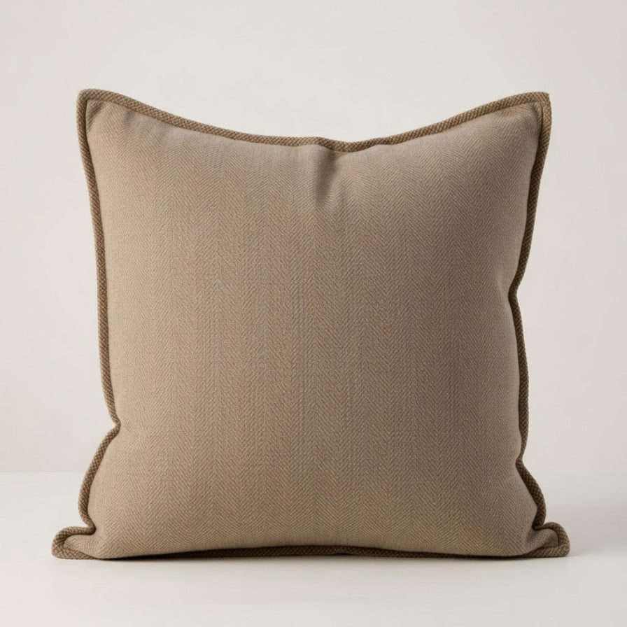Beige pillow with brown trim on a white background