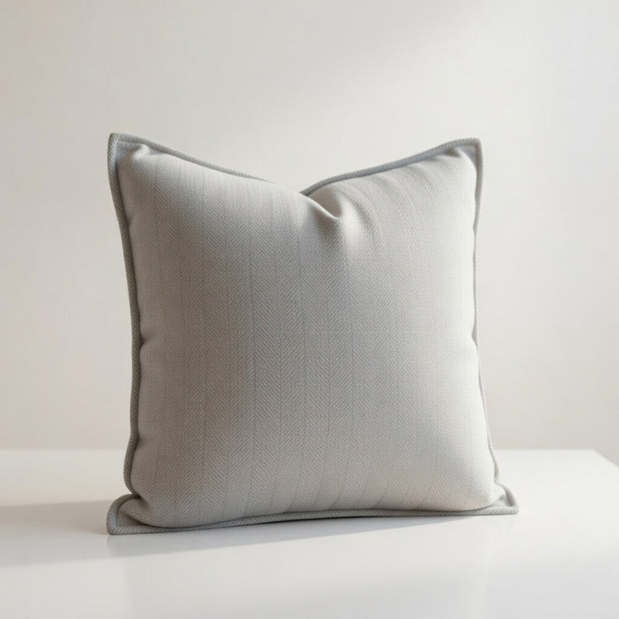 Gray textured pillow on a white surface with a light gray background