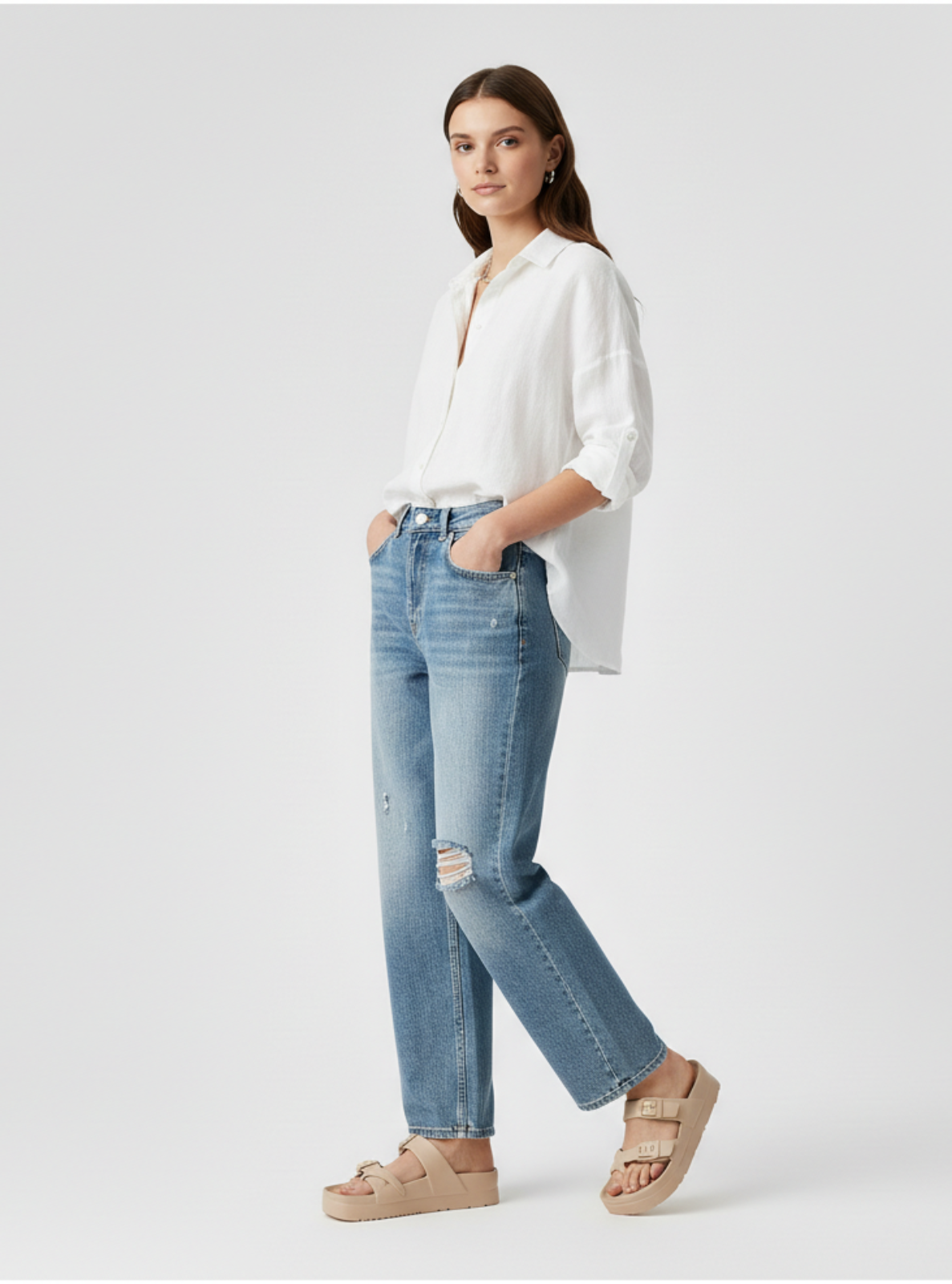 Woman wearing a white blouse and blue jeans on a light gray background