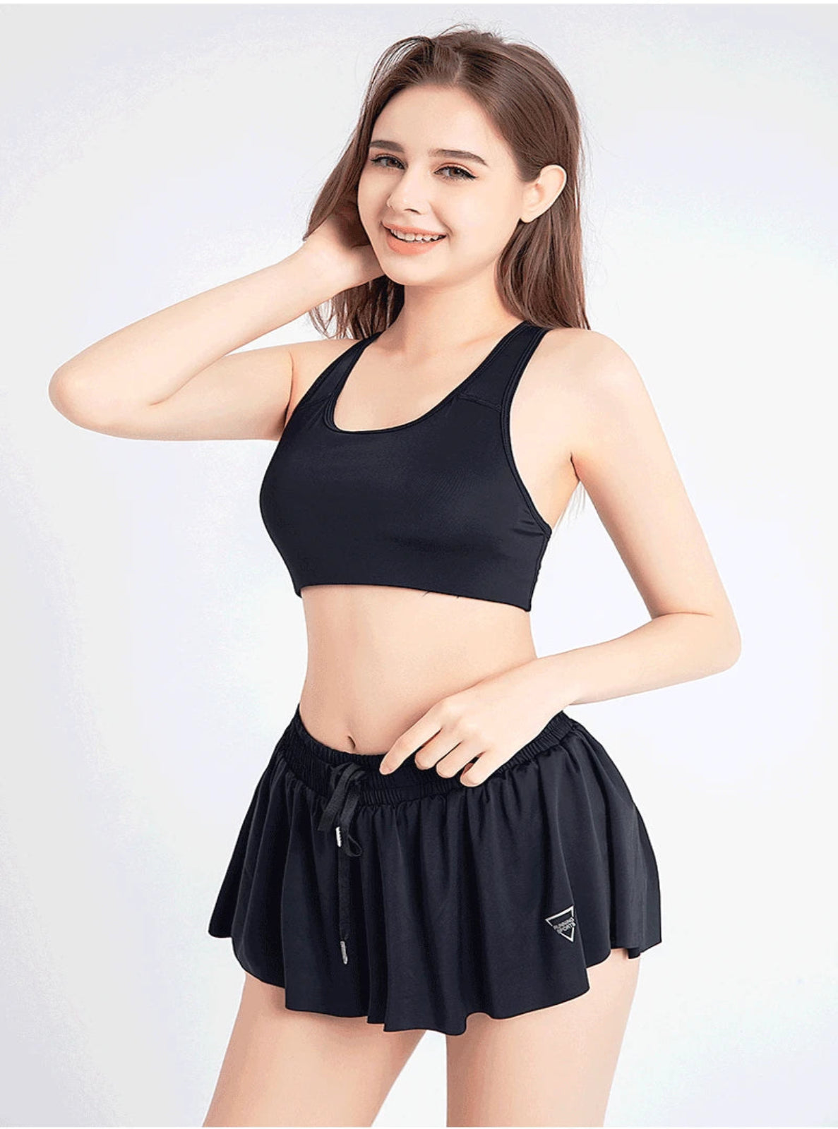 Woman wearing a black sports bra and shorts on a white background