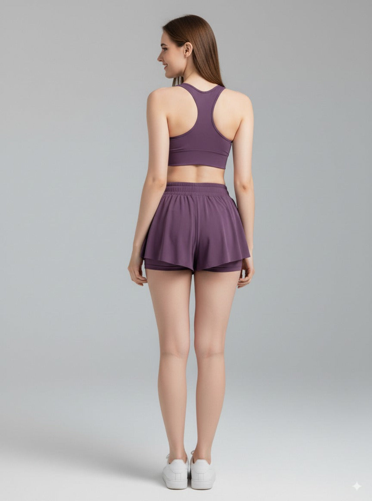 Woman wearing a purple athletic outfit on a gray background
