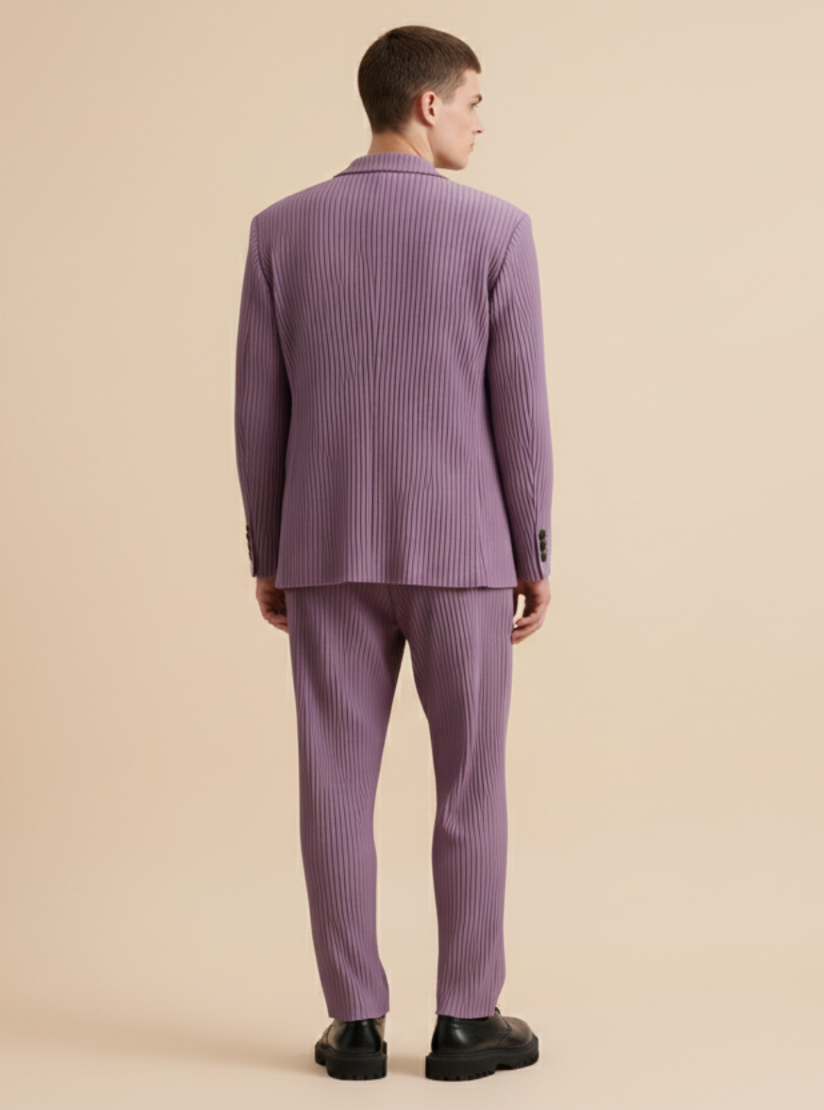 Man wearing a purple suit standing against a beige background