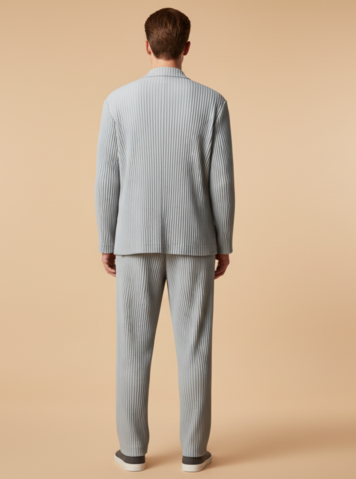 Man wearing a light blue ribbed sweater and matching pants on a beige background