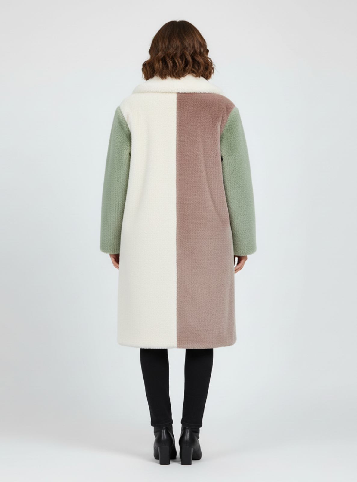 Woman wearing a long, color-blocked coat on a white background