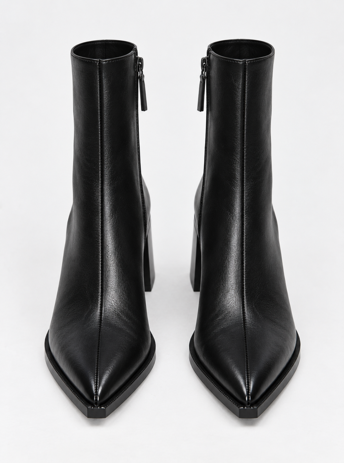 A pair of black leather pointed-toe ankle boots with high block heels and side zippers, shown from a front-facing perspective on a light gray background.