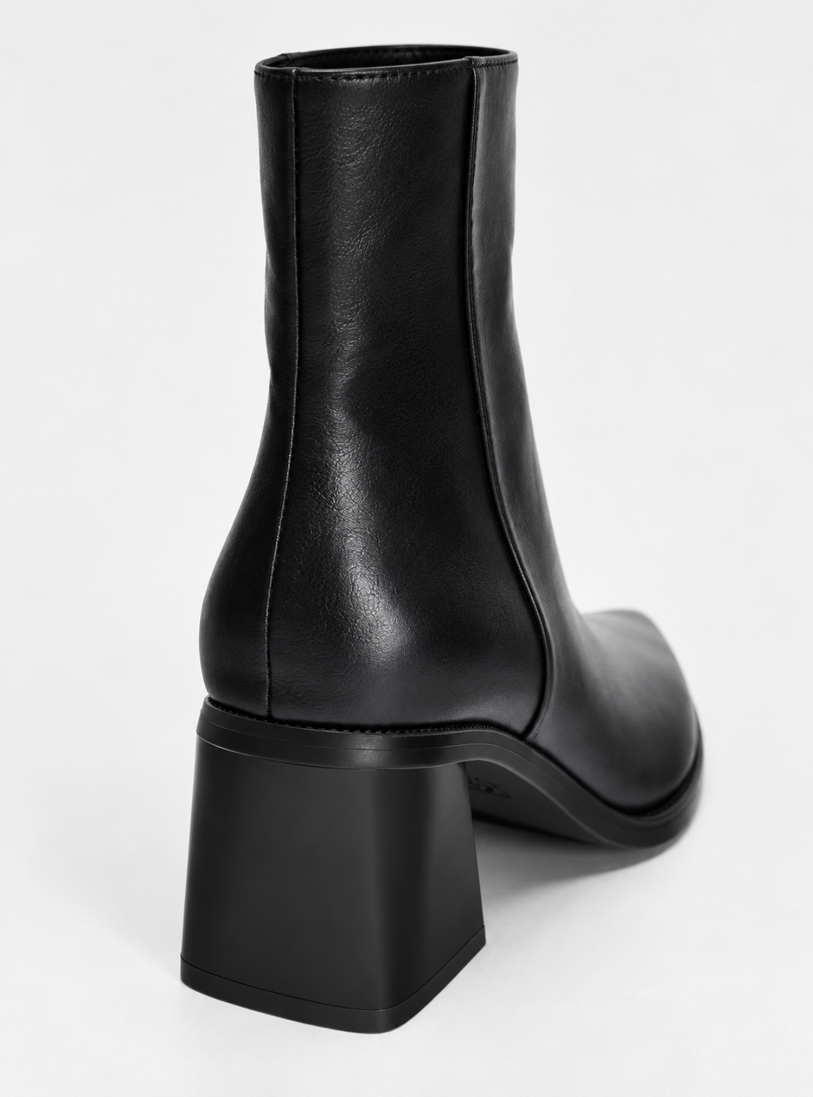 A black leather ankle boot with a chunky block heel, shown from a rear three-quarter angle on a light gray background.