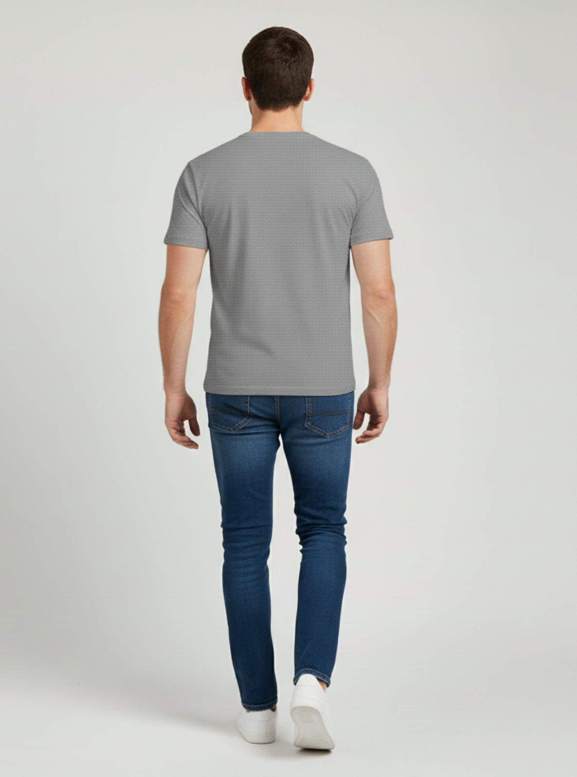 Man wearing a gray t-shirt and blue jeans on a white background
