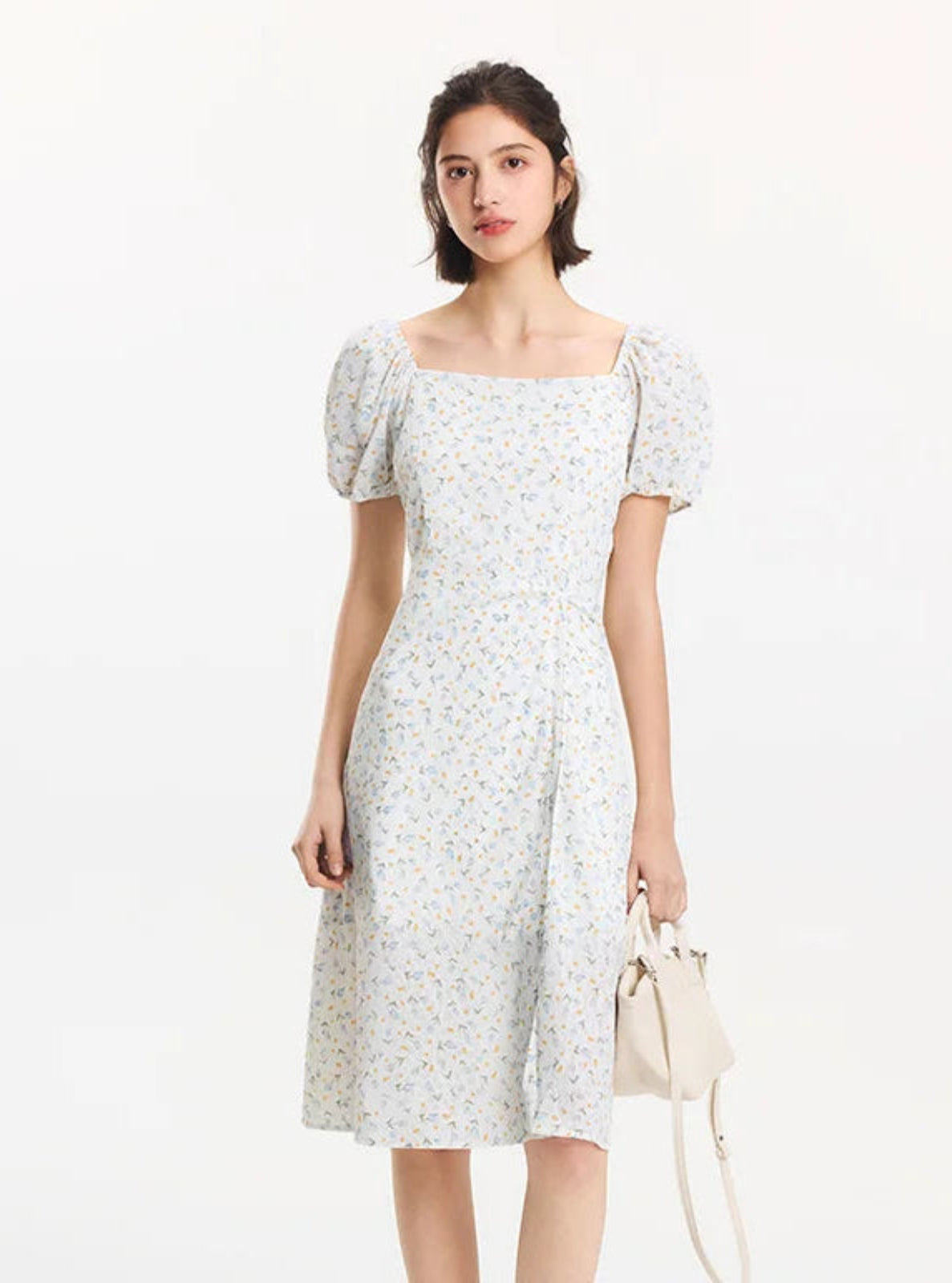 Woman wearing a light-colored floral dress on a white background