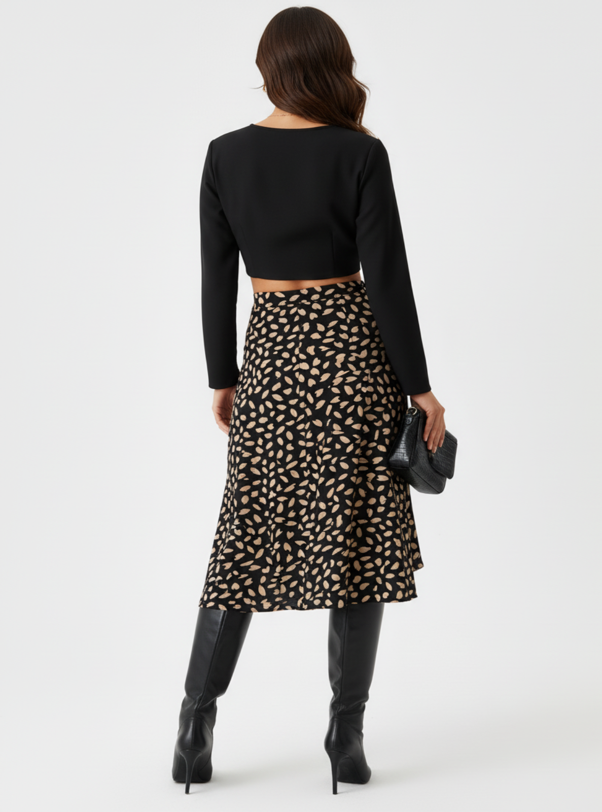 Woman wearing a black top and patterned skirt on a white background