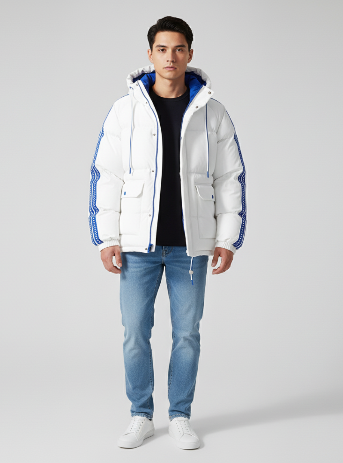 Man wearing a white puffer jacket with blue accents, black shirt, and blue jeans on a gray background