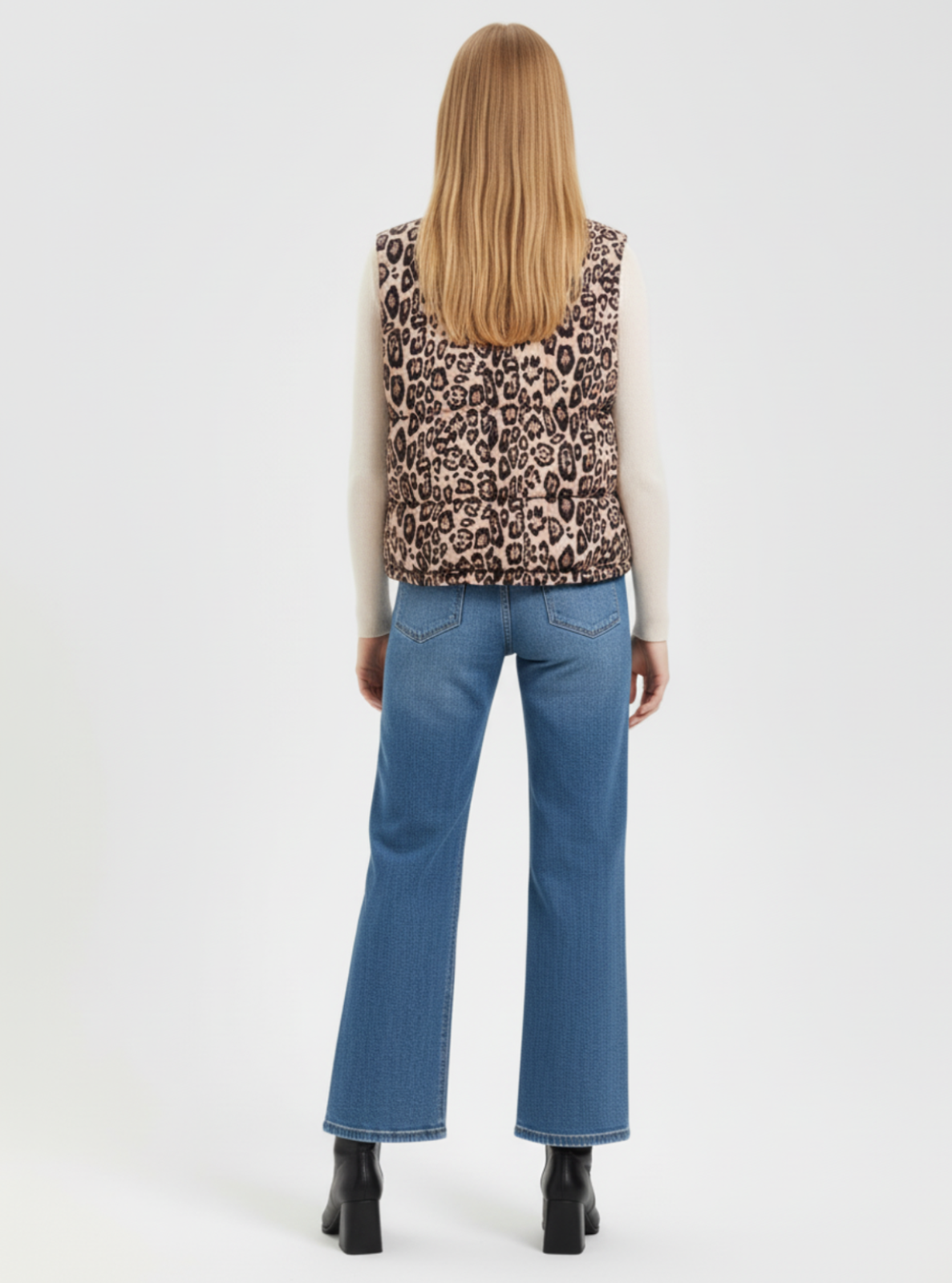 Person wearing a leopard print sleeveless top and blue jeans on a white background
