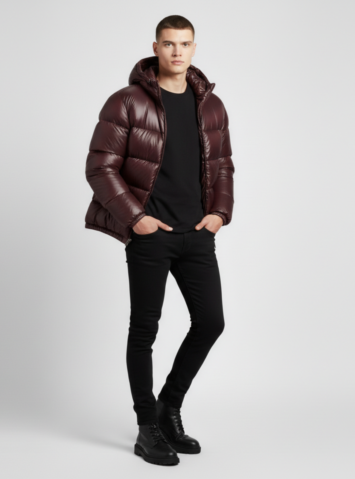 Man wearing a brown puffer jacket, black shirt, and jeans on a light gray background