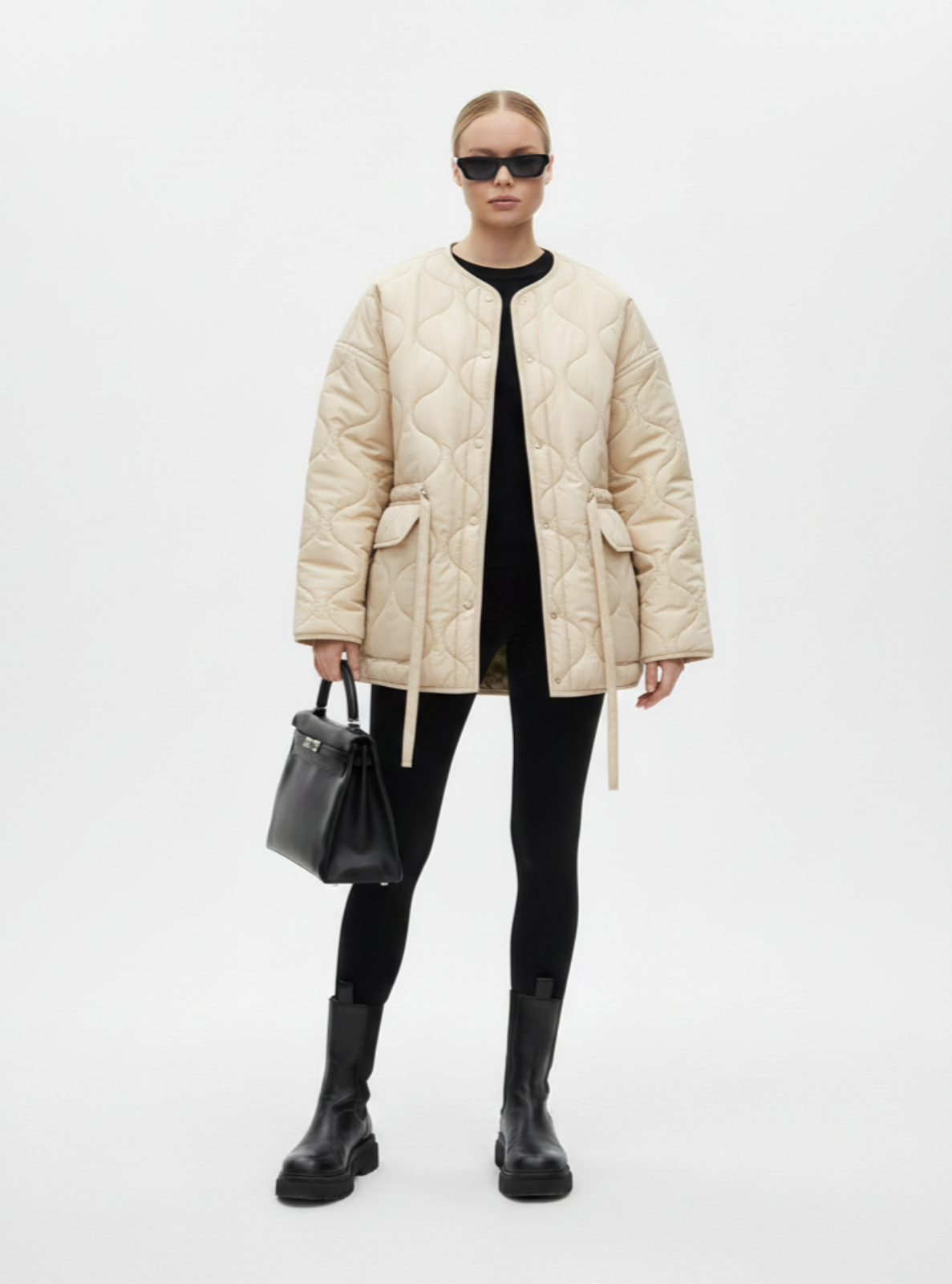 Person wearing a beige puffer coat, black pants, and boots on a white background