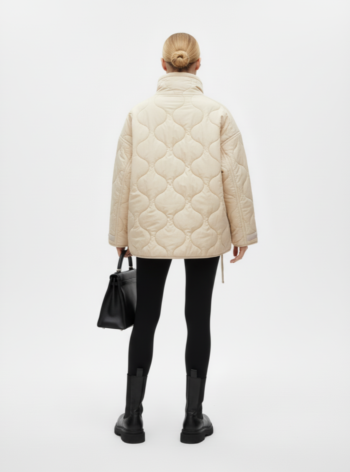 Person wearing a beige quilted jacket on a white background