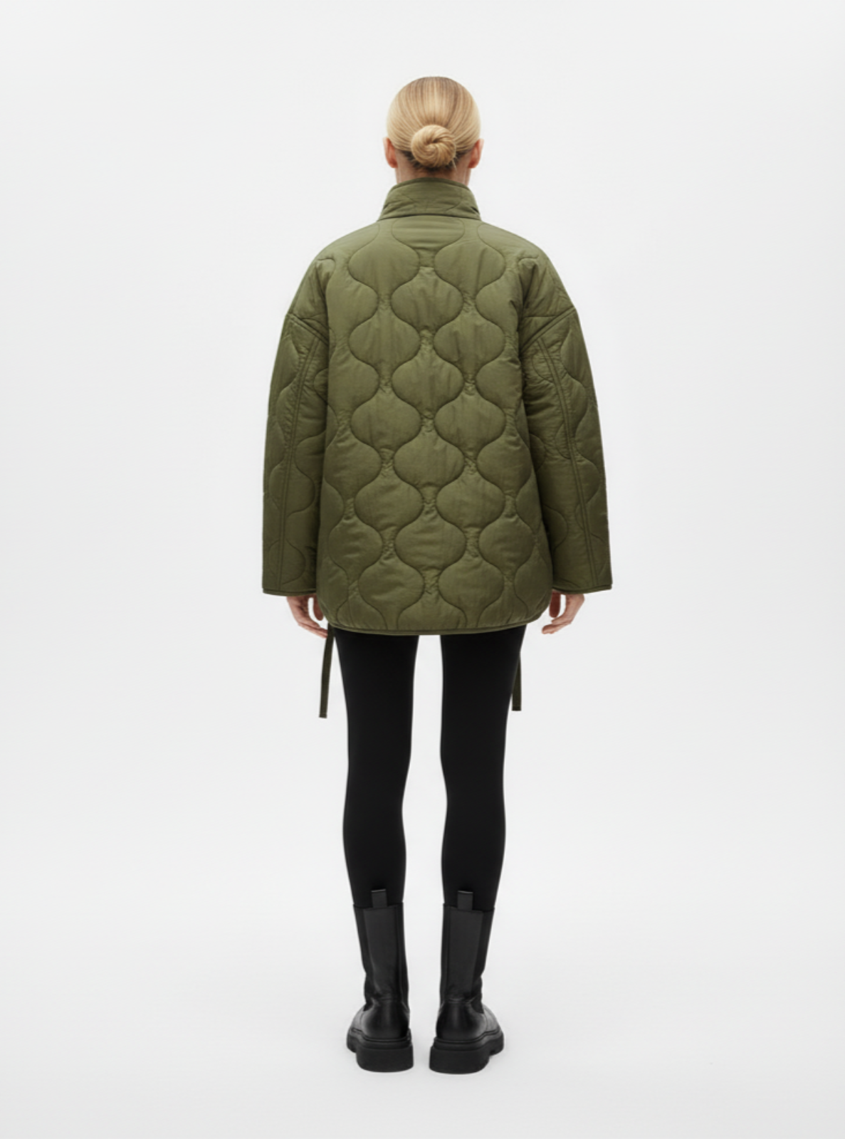 Person wearing a green quilted jacket on a white background
