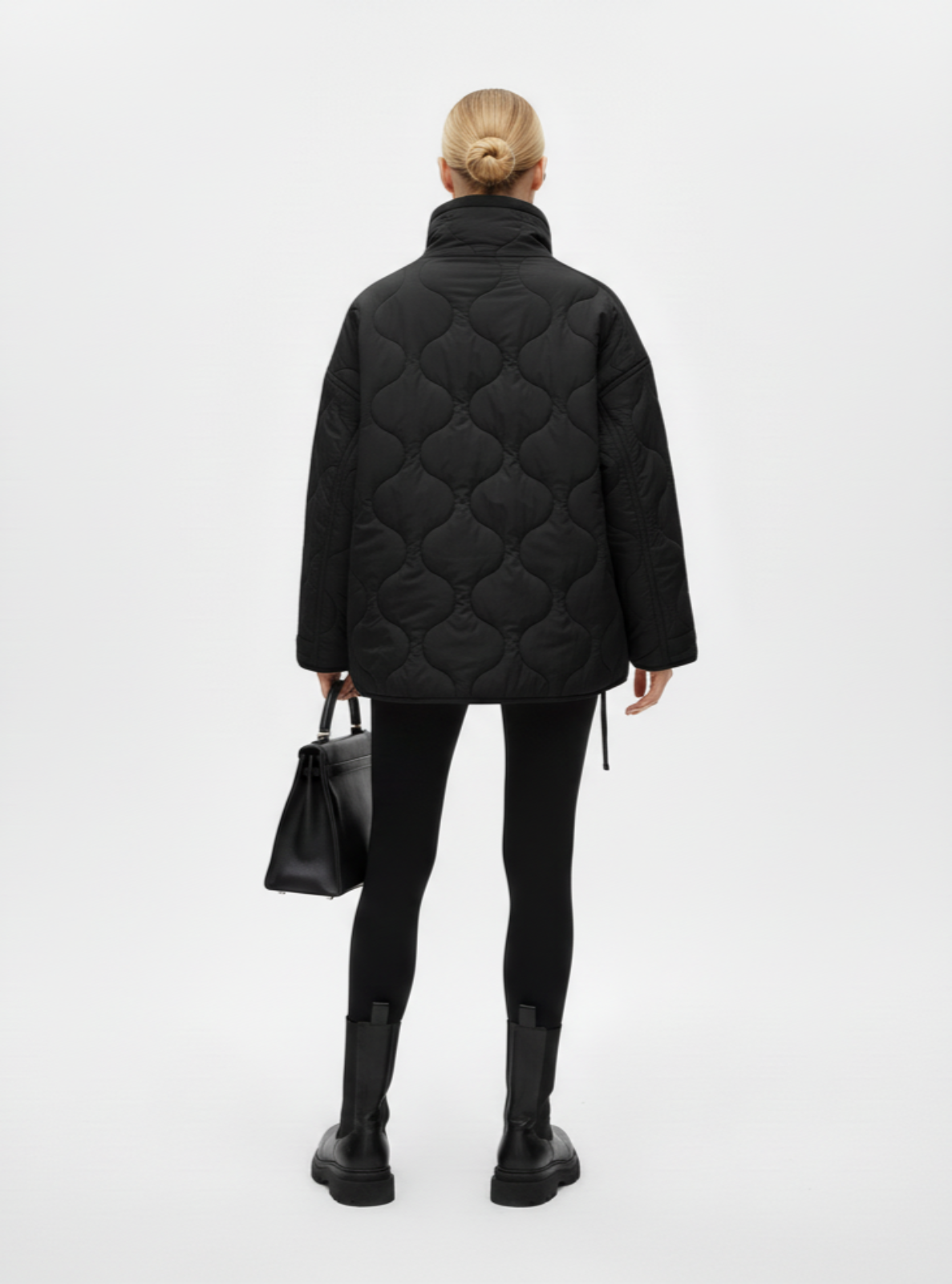 Person wearing a black quilted jacket on a white background