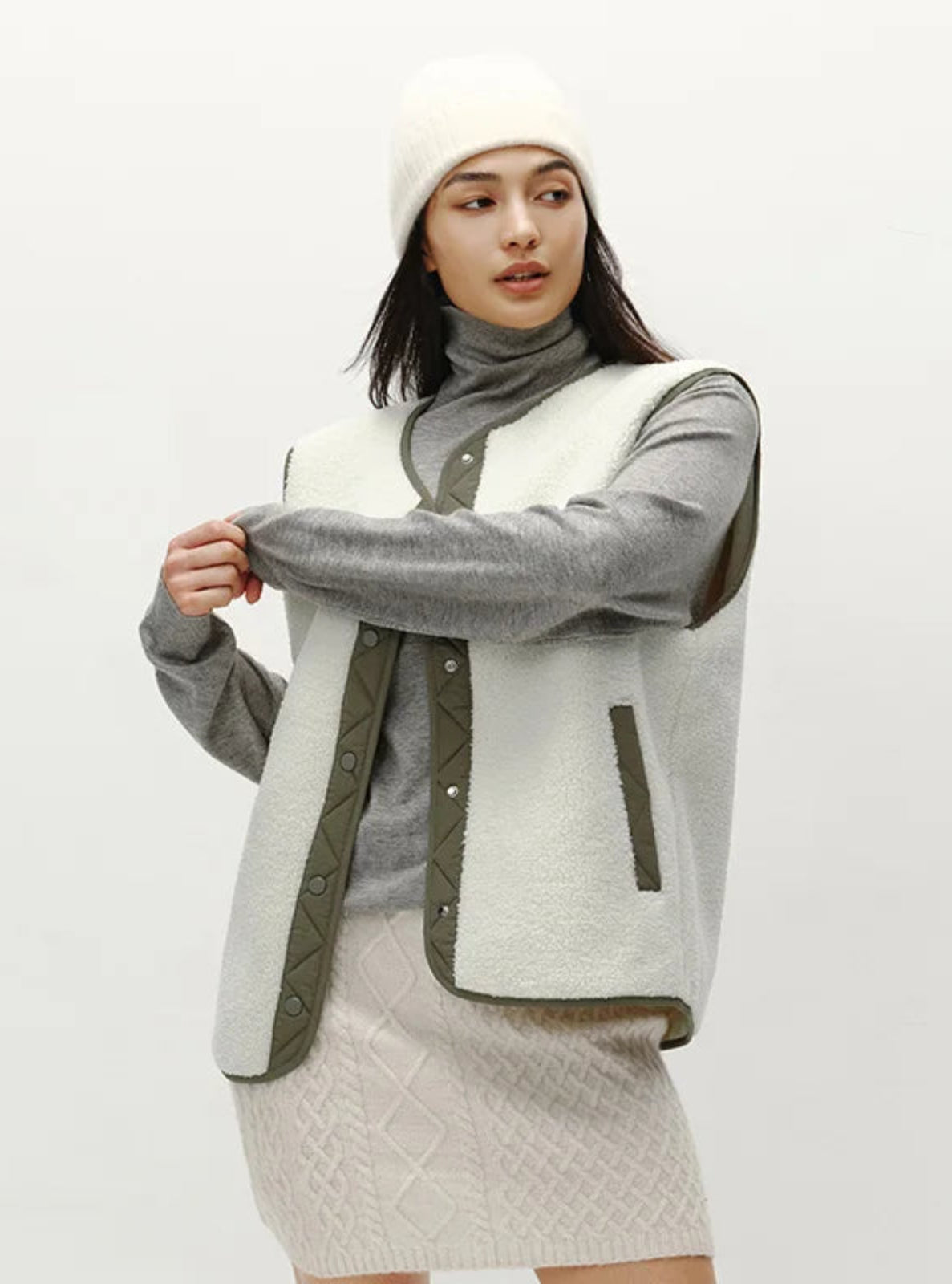 Woman wearing a gray and white quilted jacket on a white background