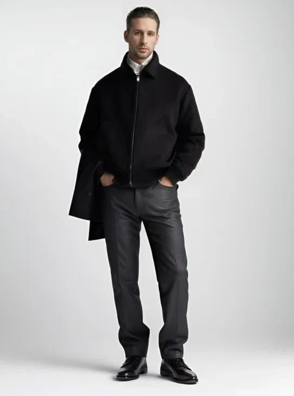 Man wearing a black coat and dark pants on a white background